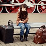 Un enfant en attente à l'arrivé à la gare avec ses bagages