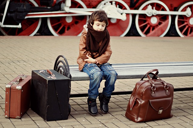 Un enfant en attente à l'arrivé à la gare avec ses bagages